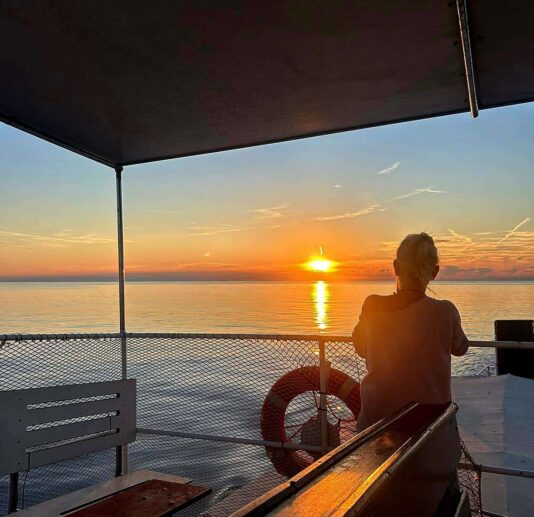 Person watching a serene Adriatic sunset from a boat.